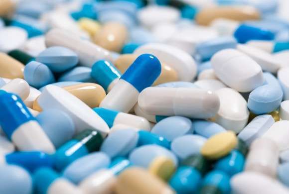 Cápsulas e comprimidos de medicamentos espalhadas nas cores azul, amarelo e branco