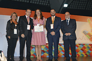 Dra. Patrícia Moriel (ao centro)  recebe o prêmio de melhor trabalho dos diretores do CRF-SP e do presidente do Cosems