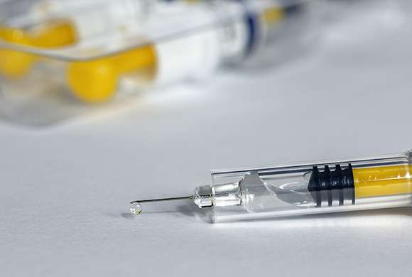 Foto mostra uma seringa de vacina sobre uma mesa