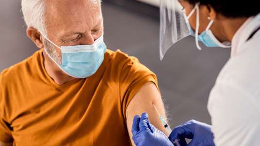 Senhor de cabelo branco recebe vacina no braço