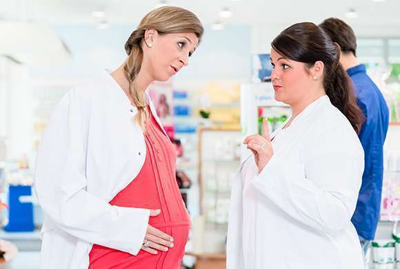 Mulher grávida conversa com farmacêutica.