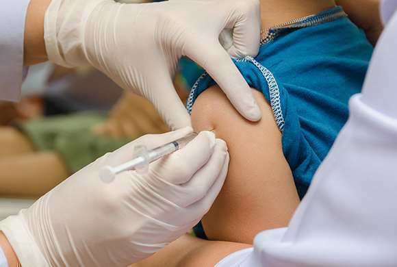 Imagem de uma pessoa aplicando uma vacina no braço de uma criança