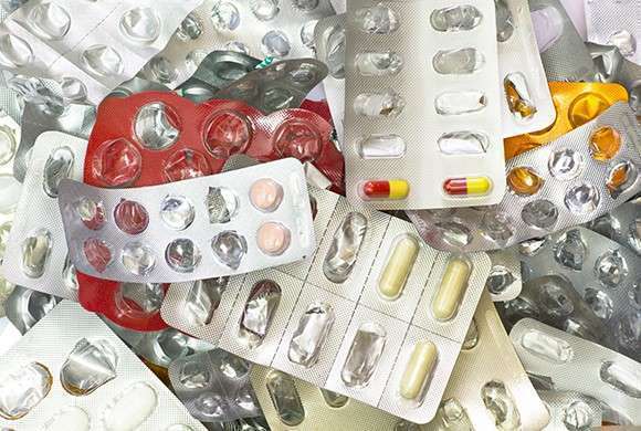 Foto de diversas embalagens vazias ou começadas de medicamentos em cápsulas ou comprimidos esparramados uns sobre os outros